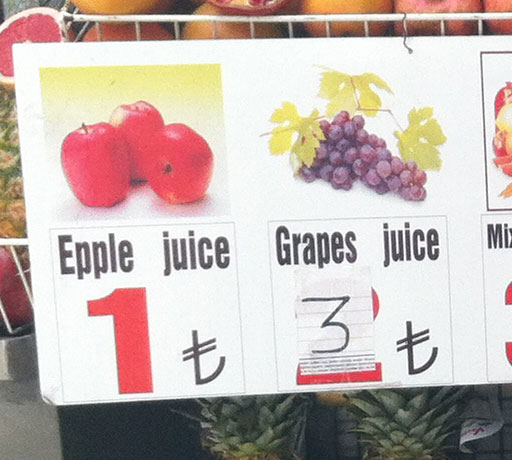 Close up of the fruit stand sign of misspelled juices: Epple juice and grapes juice.