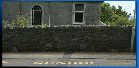 The word "Sckool" is erroniously written in yellow paint on the road in front of a school.