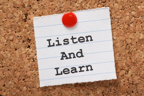 Corkboard with a piece of paper tacked on that has the message: Listen and Learn.